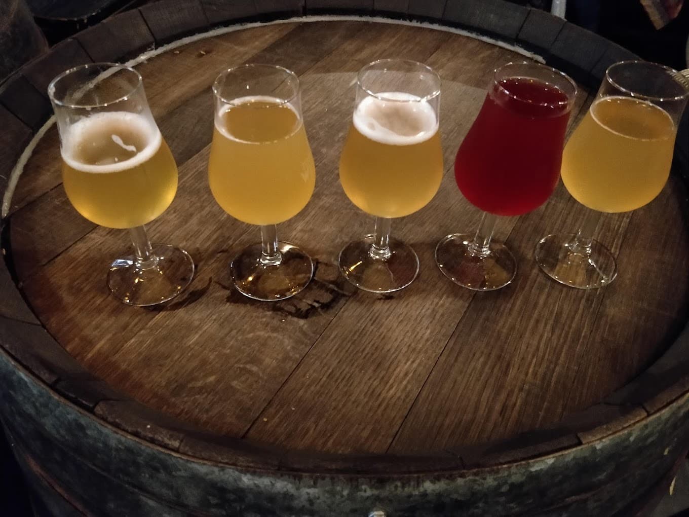 A flight of five craft beers served on a barrel top